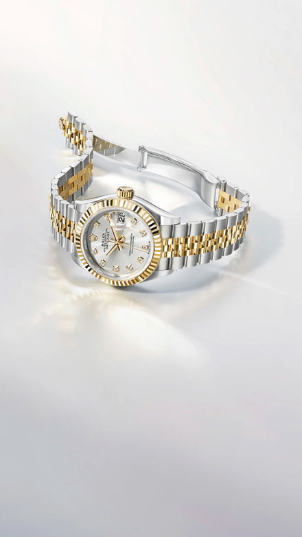 A two-tone Rolex Lady Datejust with a silver and gold metal bracelet, a gold fluted bezel, and a white dial with diamond hour markers, displayed on a clean white background.